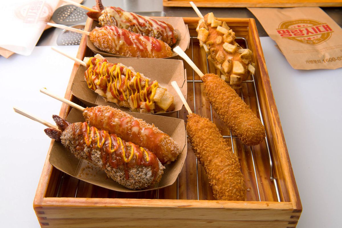 Eight Korean street style hot dogs, deep fried and served on a stick.