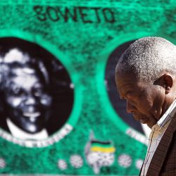 A man walks past a fabric bearing a portrait of former president Nelson Mandela in Soweto, South Africa, Monday June 10, 2013.  Former President Nelson Mandela's condition remains serious but stable on Monday, his third day in a Pretoria hospital, the South African government said. "His condition is unchanged," the office of President Jacob Zuma said in a brief statement.   (AP Photo/Themba Hadebe)