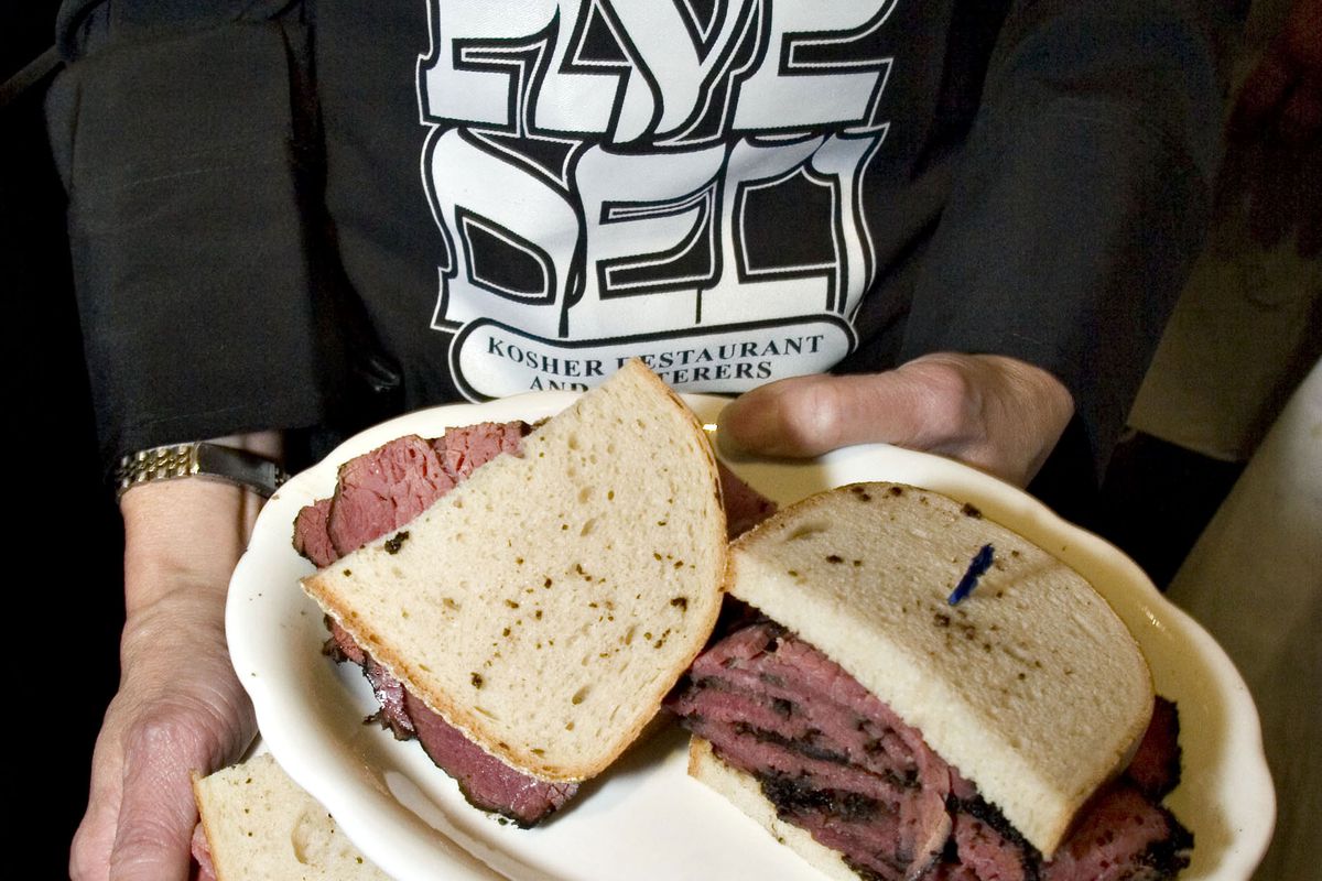 A waitress holds pastrami sandwiches inside the 2nd Avenue D