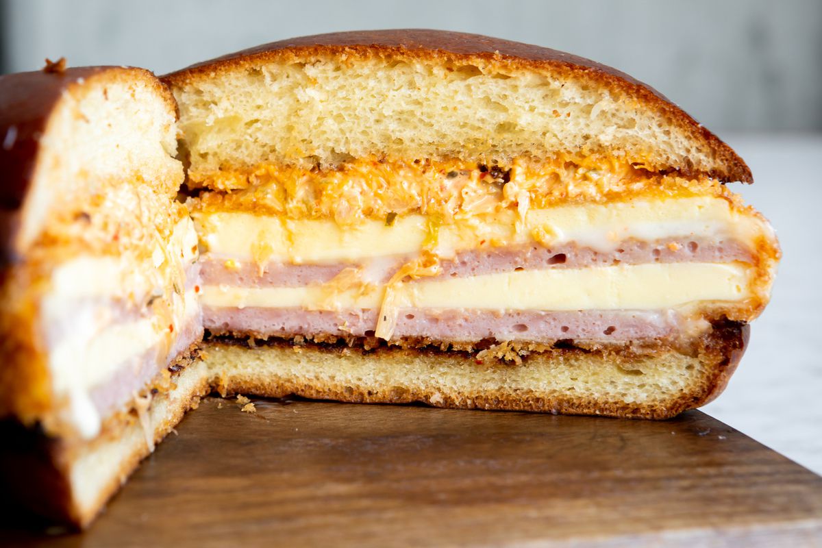 A cross section of the breakfast sandwich reveals layers of Spam, steamed egg, and melted cheese
