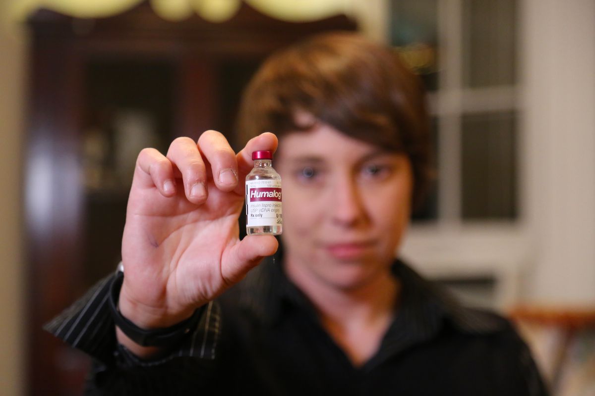 A person holding a vial of insulin toward the camera.