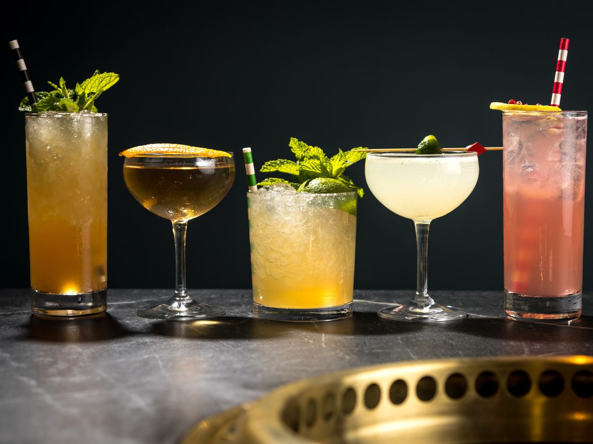 A lineup of five mixed cocktails on the bar at Cote