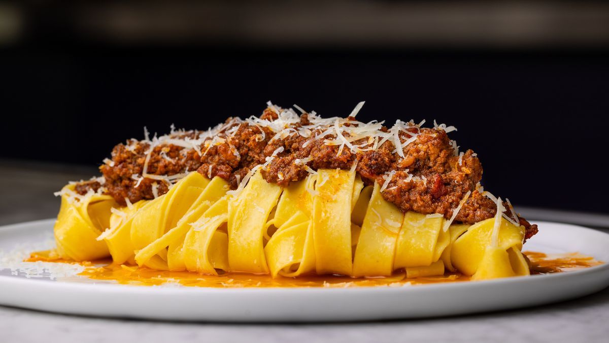 A close up side shot of a wide pasta noodle with bolognese-style sauce on top at new LA restaurant Vicini.