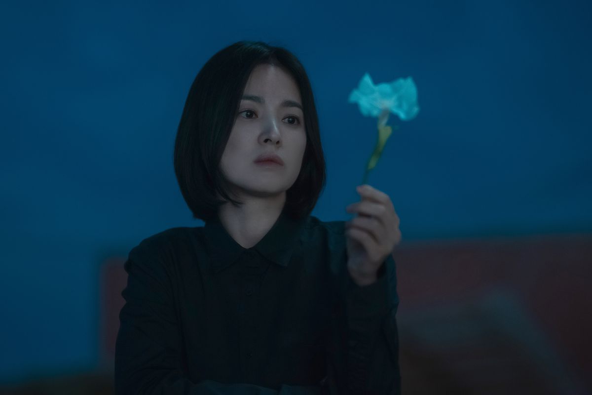 Song Hye-kyo as Moon Dong-eun holding a white flower and looking at it wistfully