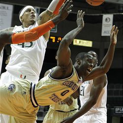 Georgia Tech guard Mfon Udofia (0) is fouled by Miami guard Durand Scott (not shown) in the first quarter. Miami center Julian Gamble (45), left, looks on.