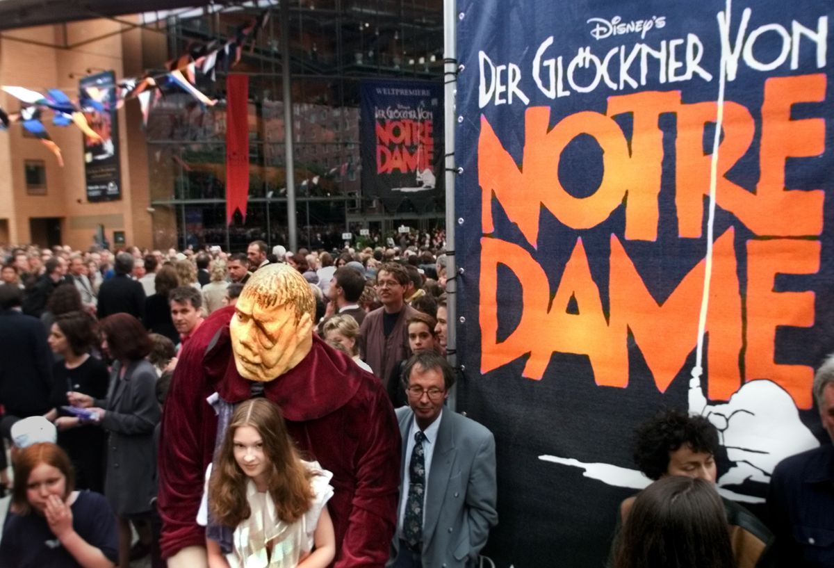 In this Saturday June 5, 1999 file photo, a girl dressed as Esmeralda carries a dummy of the character Quasimodo as people go into the new concert hall at Potsdamer Platz in Berlin, Germany, before the world premiere of the musical “The Hunchback of Notre