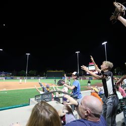 Fans clamber to catch a ball thrown from a player as they enjoy a Salt Lake Bees baseball game at Smith's Ballpark in Salt Lake City on Wednesday, June 5, 2019.