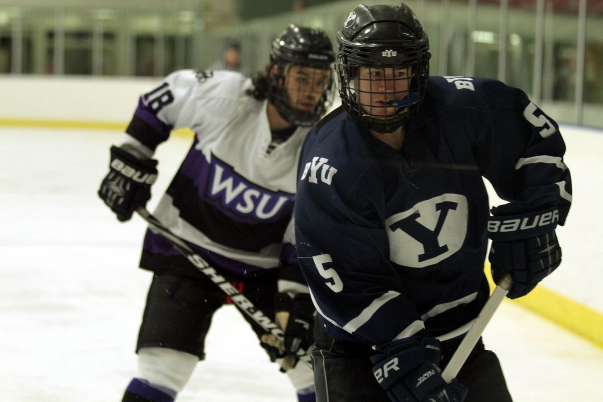BYU's Josh Patrick (5) plays the puck against the boards as Weber State's Koda Coleman (18) closes in.