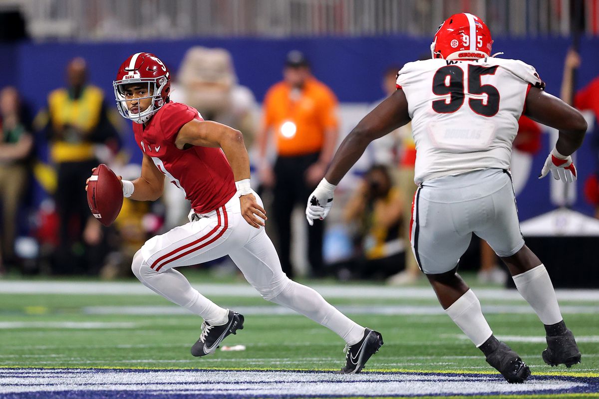 Bryce Young of the Alabama Crimson Tide carries the ball as Devonte Wyatt of the Georgia Bulldogs defends in the second quarter of the SEC Championship game at Mercedes-Benz Stadium on December 04, 2021 in Atlanta, Georgia.