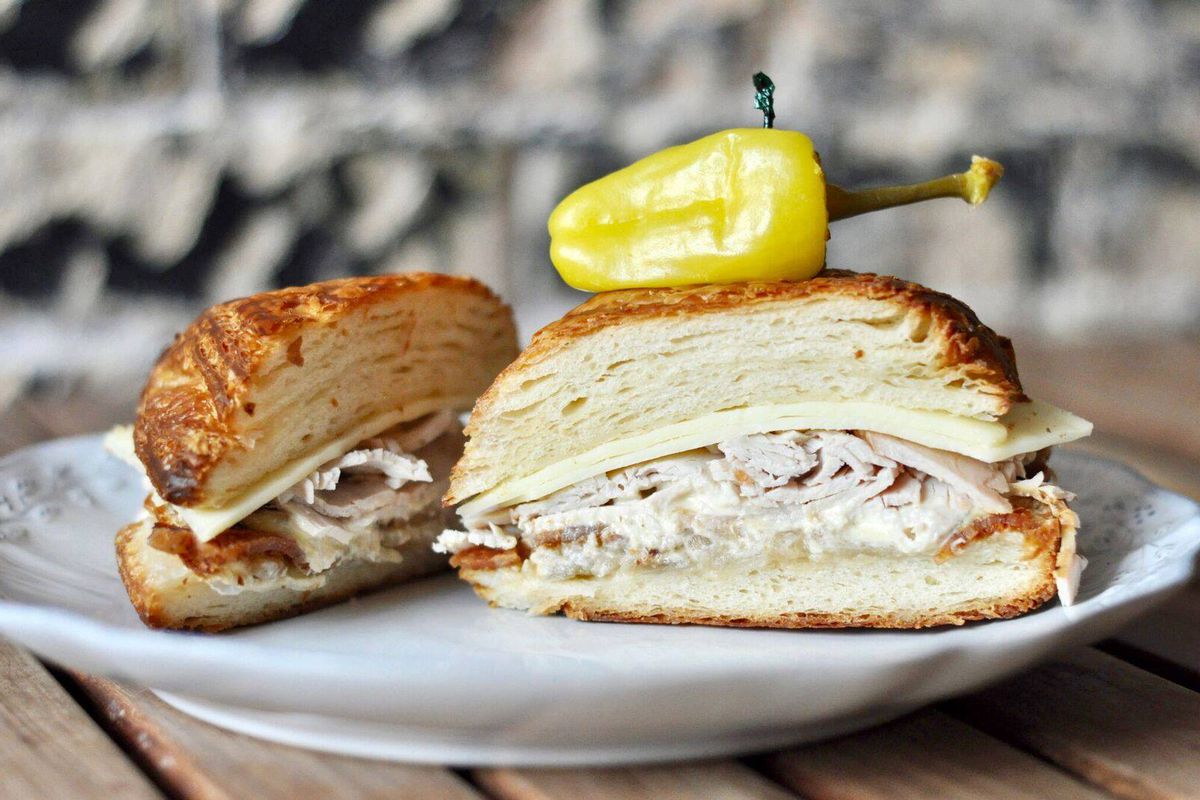 A halved croissant sandwich with layers of turkey.