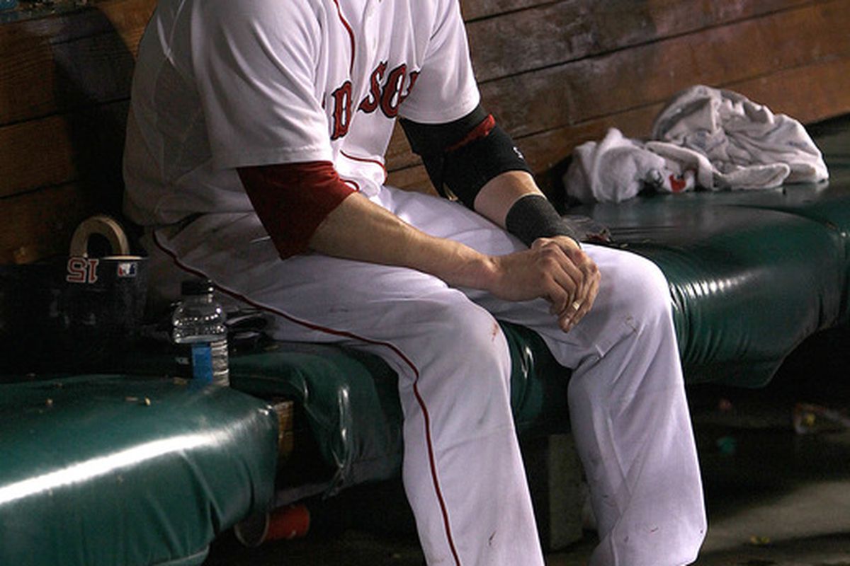 Dustin Pedroia of the Boston Red Sox sits in the dugout alone after a 7-5 loss to the Baltimore Orioles at Fenway Park in Boston, Massachusetts. (Photo by Jim Rogash/Getty Images)