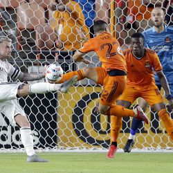 Real Salt Lake midfielder Albert Rusnak, left, attempts a shot on goal as Houston Dynamo midfielder Matias Vera (22) defends and Teenage Hadebe (18) and goalkeeper Marko Maric (1) look on during the second half of an MLS soccer match Saturday, July 31, 2021, in Houston.