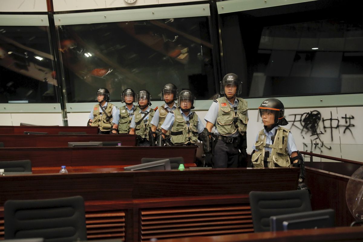 Police officers with protective gear retake the meeting hall of the legislative council building in Hong Kong during the early hours of Tuesday, July 2, 2019. Protesters’ graffiti can be seen on the walls in the background.