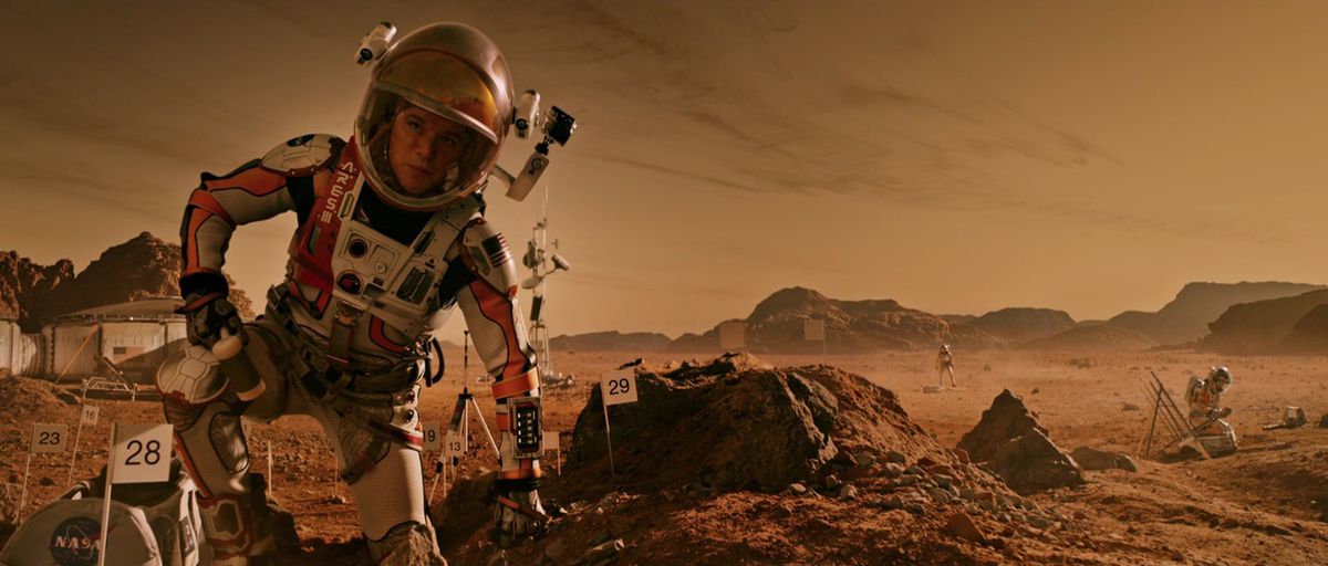 Matt Damon in an orange and white spacesuit on Mars in The Martian.