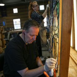 David Bradford, front, and his wife, Martha Bradford, clean a glass panel that is part of“The Roots of Knowledge,” a 200-foot-long stained glass installation for Utah Valley University, at Holdman Studios in Lehi on Friday, Nov. 4, 2016. The university announced a $1.5 million donation from philanthropists Marc and Deborah Bingham that will enable the completion of the massive stained glass installation.
