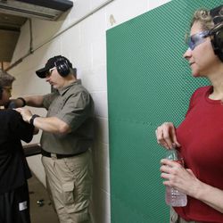 In this Sunday, May 19, 2013, photo, Cheryl Strain, right, watches as instructor Scott Stevens, center, shows her son Rory, 12, how to properly hold a shotgun at a shooting range in Houston. The Strains live in the first residential area being trained and equipped by a nonprofit that is giving away free shotguns to single women and neighborhoods with high crime rates. 