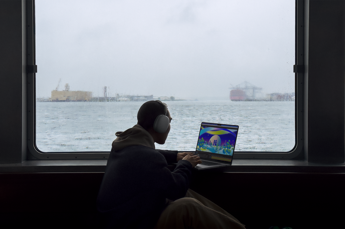 An image of somebody using a MacBook Pro by a window near water.