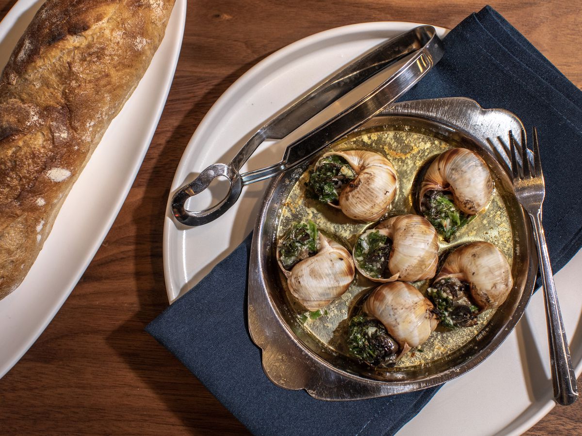 A classic dish of French escargot swimming in garlic herb butter served with a demi baguette from Foundation Social Eatery in Alpharetta, GA.