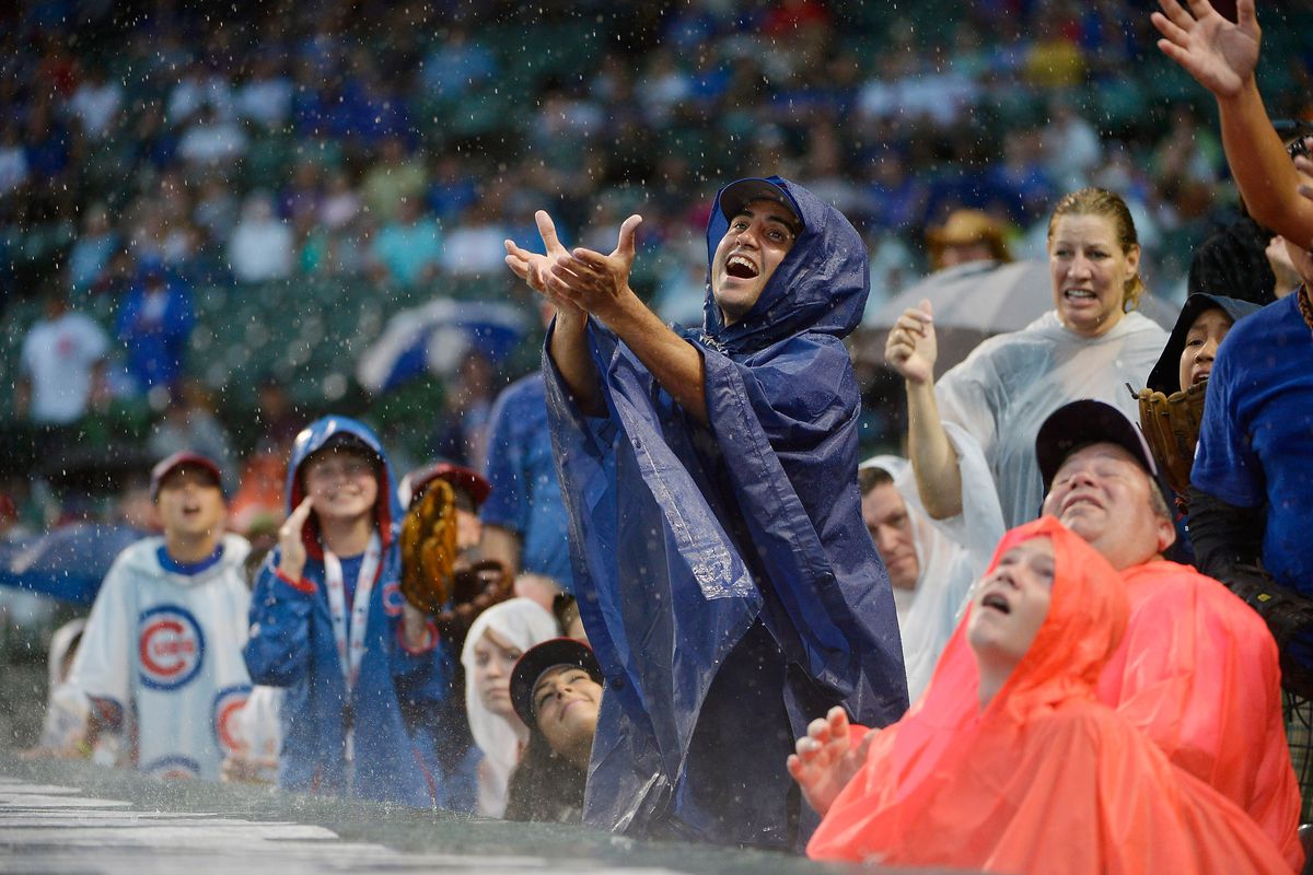 Fans watch a ball as the rain falls during the Chicago Cubs and Colorado Rockies game at Wrigley Field in Chicago, Illinois. The Cubs defeated the Rockies 5-0 in a rain-shortened eight inning game.  (Photo by Brian Kersey/Getty Images)