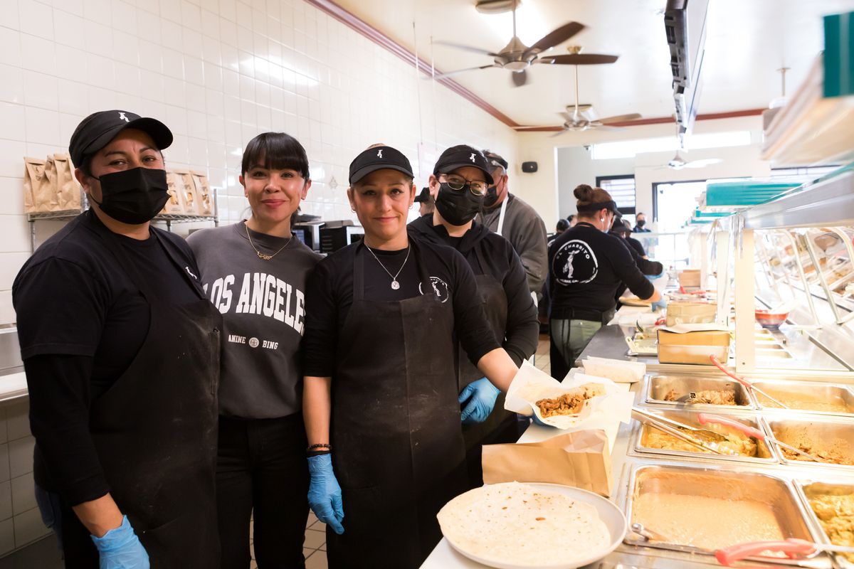 Three employees of El Charrito stand behind the steam table, posing for a photo with Kenya Moncada, second from left.