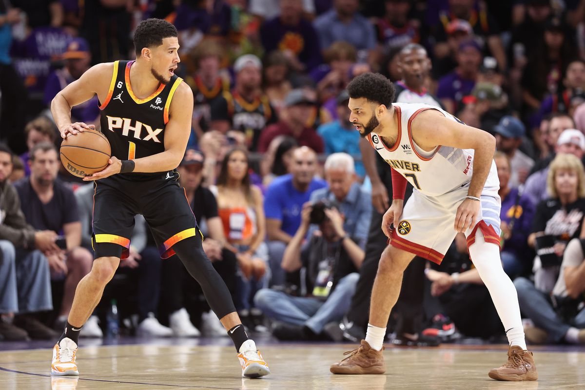 PHOENIX, ARIZONA - MAY 05: Devin Booker #1 of the Phoenix Suns handles the ball against Jamal Murray #27 of the Denver Nuggets during the first half of Game Three of the NBA Western Conference Semifinals at Footprint Center on May 05, 2023 in Phoenix, Arizona.