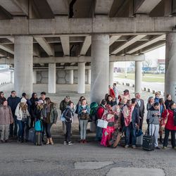 People stand near Brussels airport after being evacuated following  explosions that rocked the facility in Brussels, Belgium, Tuesday March 22, 2016. Authorities locked down the Belgian capital on Tuesday after explosions rocked the Brussels airport and subway system, killing  a number of people and injuring many more. Belgium raised its terror alert to its highest level, diverting arriving planes and trains and ordering people to stay where they were. Airports across Europe tightened security. 