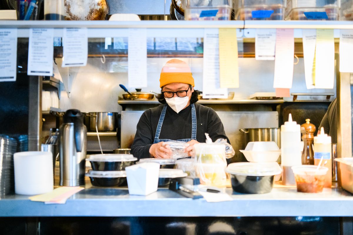 Peter Cho, the owner of restaurants Toki and Han Oak, wears a mask behind the pass in the kitchen of Toki, a Korean restaurant in Portland, Oregon.