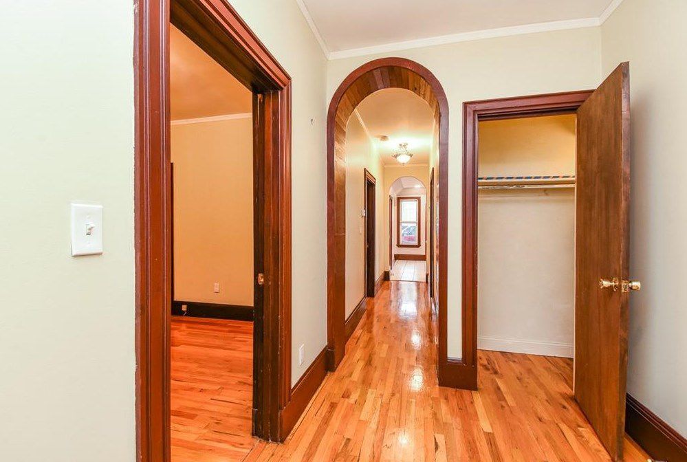 A short hallway with an opened closet and other rooms off it.