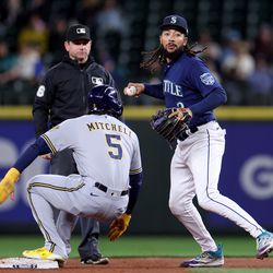 J.P. Crawford #3 of the Seattle Mariners looks to throw after tagging out Garrett Mitchell #5 of the Milwaukee Brewers at T-Mobile Park on April 17, 2023 in Seattle, Washington.