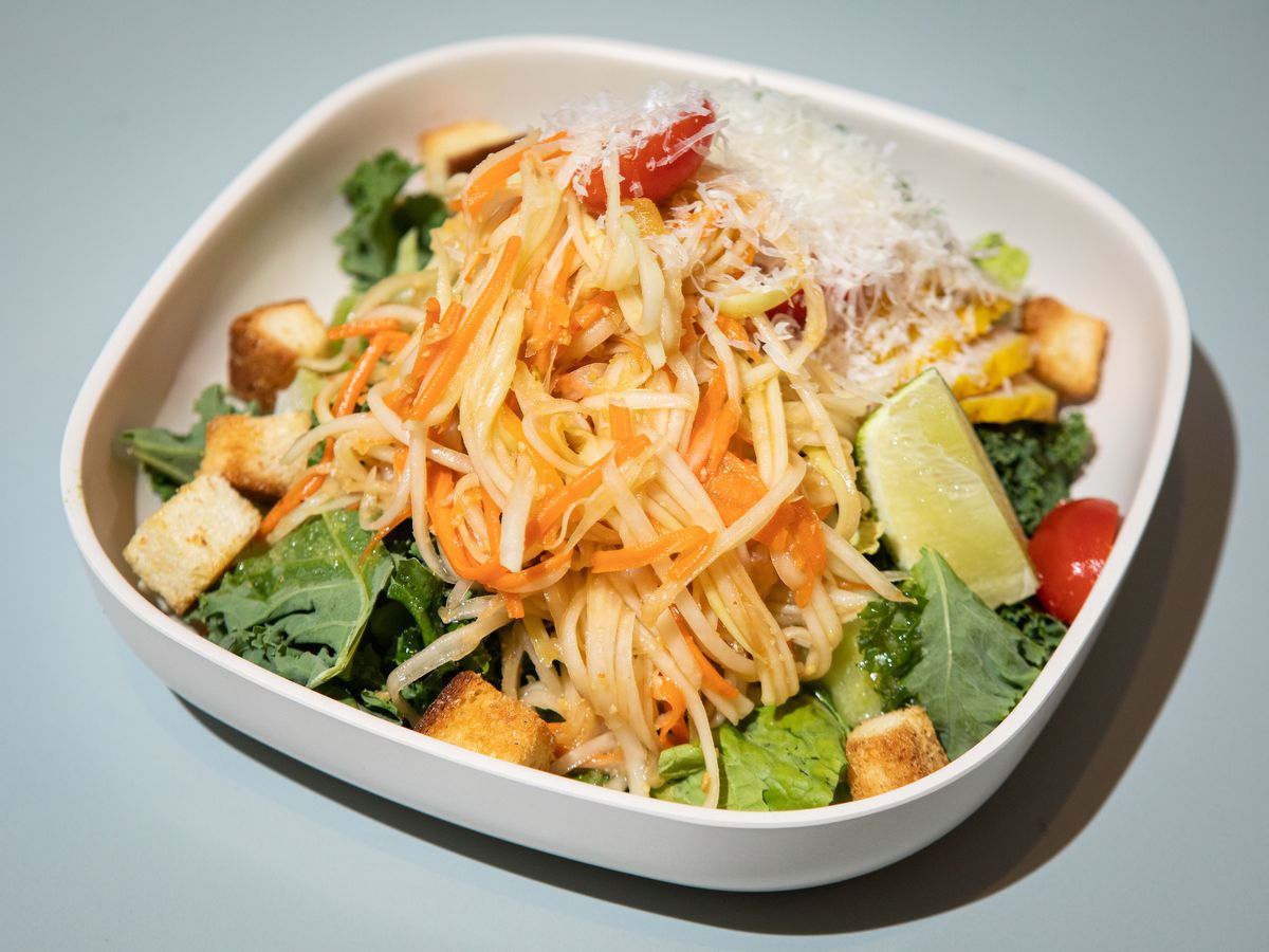 A white square shallow bowl filled with a colorful salad.