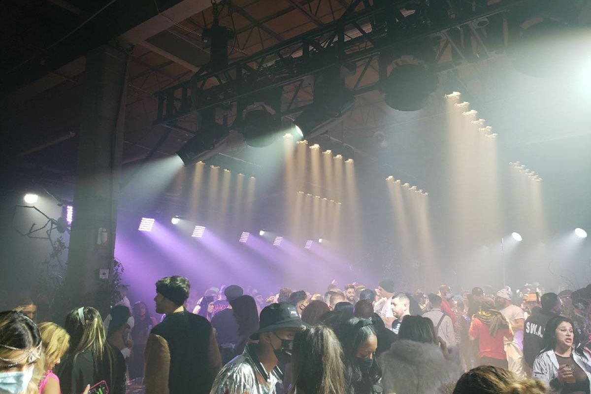 Hundreds of people crammed in a warehouse partying indoors