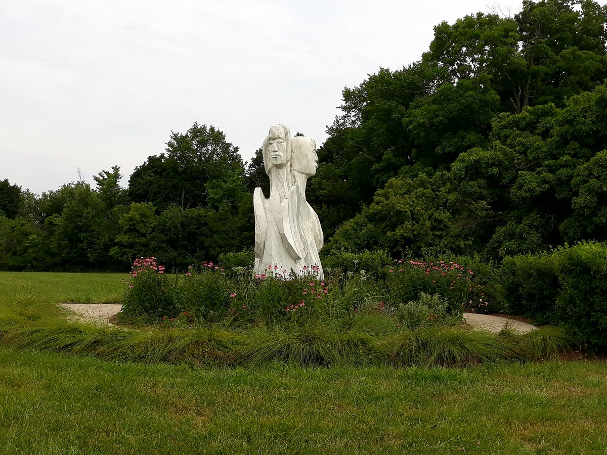 A large marble statue of two people facing away from each other but attached at the body.