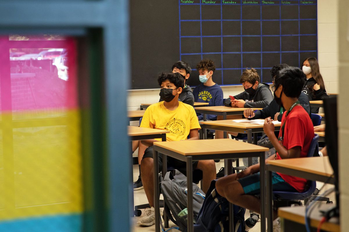 Masked students sit at their desks in school.