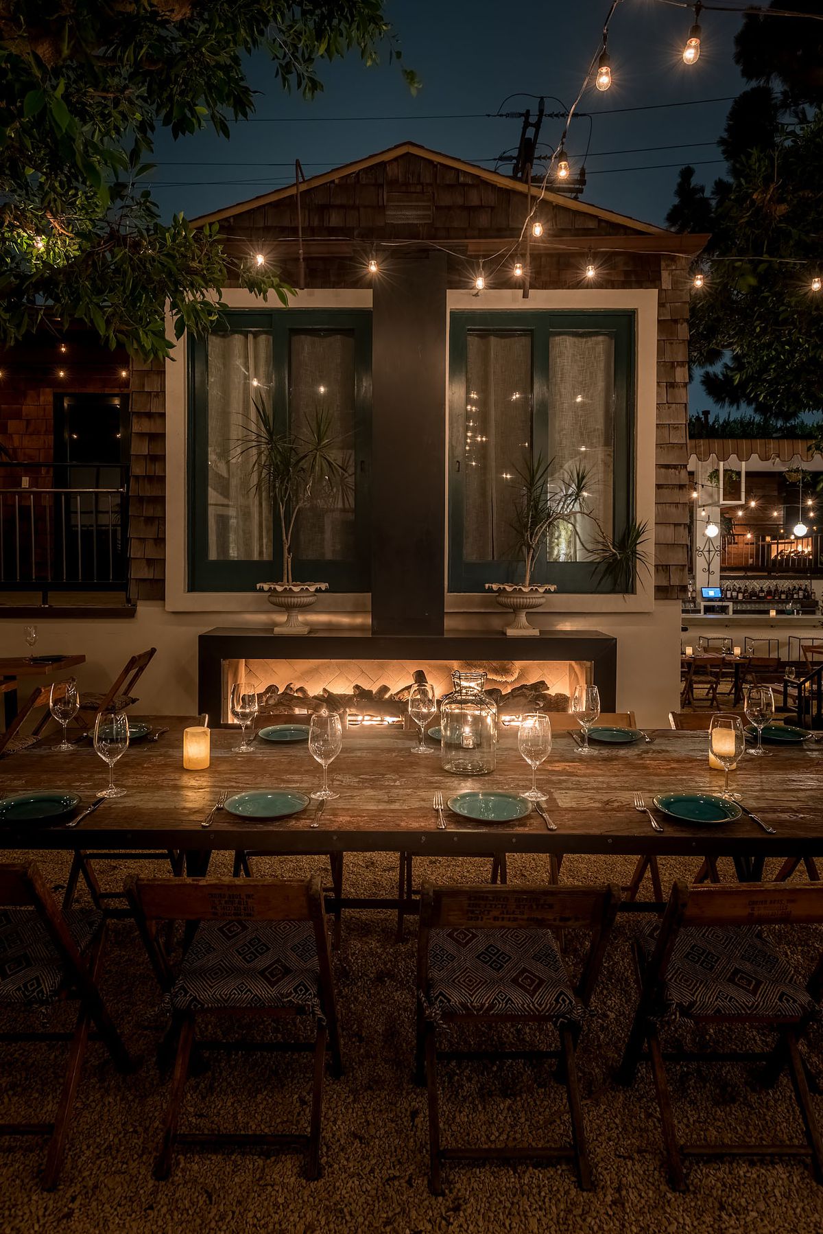 String lights outline large windows on an outdoor dinner patio.
