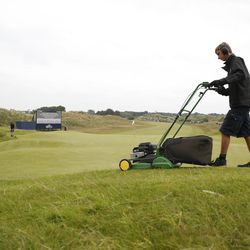 A greenkeeper mows the light rough round the edge of the sixth green during a practice round ahead of the British Open Golf Championship, at Royal Birkdale, Southport, England Wednesday, July 19, 2017.