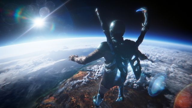 Blue Beetle looks down on Earth from space in his suit in Blue Beetle, with lens flare from the sun.