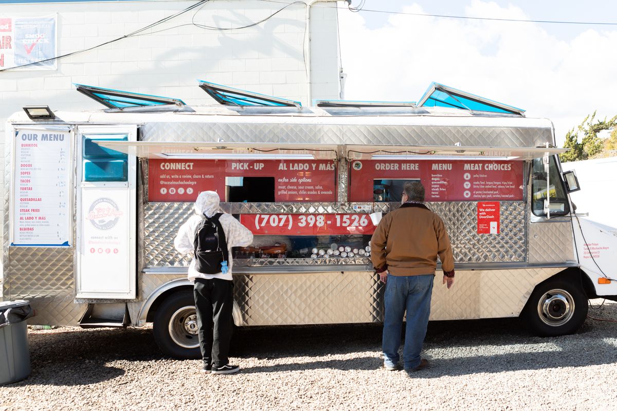 A view of a silver and red taco truck.