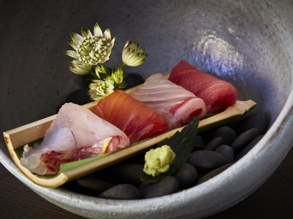 A spherical dish holding four slices of sashimi.