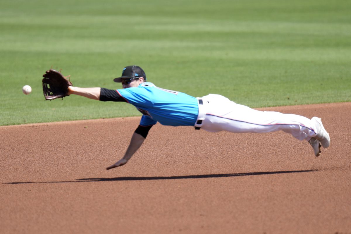 Joey Wendle #18 of the Miami Marlins dives for the ball hit by Luis Guillorme #13 of the New York Mets in the first inning of a Spring Training game at Roger Dean Stadium