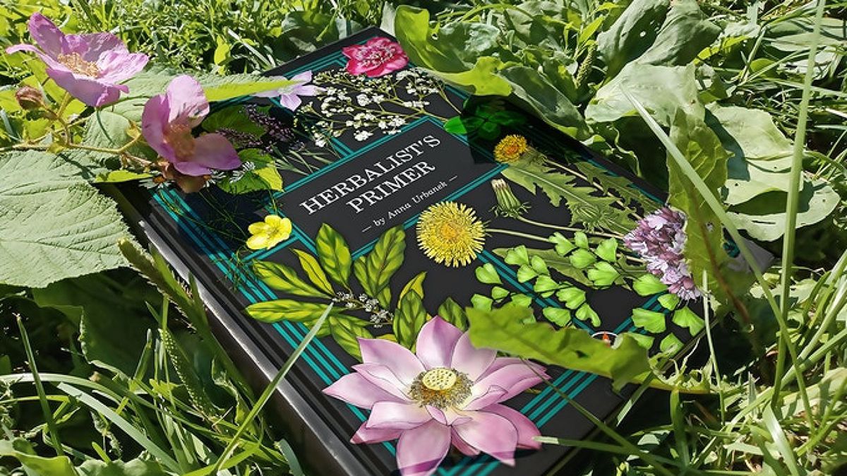 A copy of the herbalist introductory book by Anna Urbanic in the flower garden.
