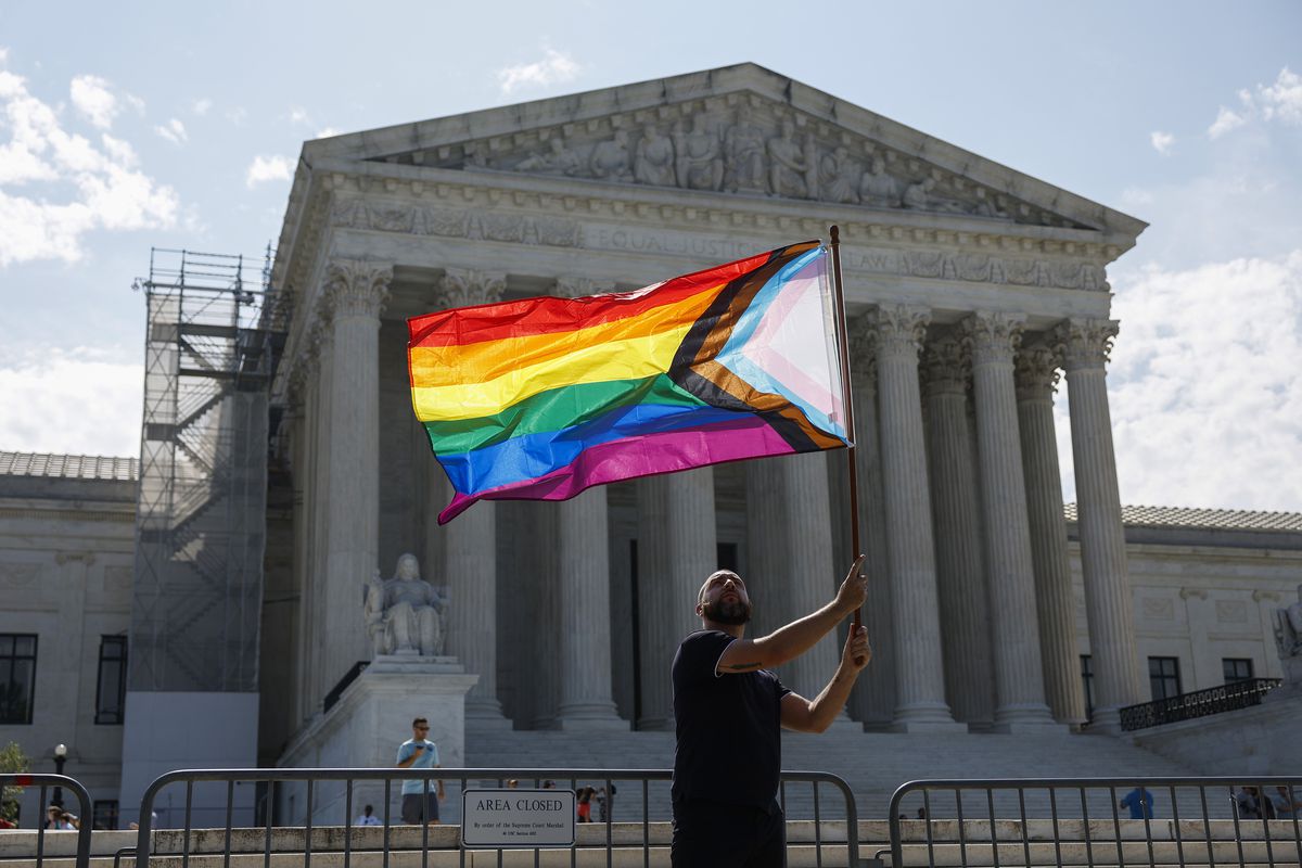 A man waves a rainbow flag in front of a tall building with a columned facade on June 26, 2023, in Washington, DC.