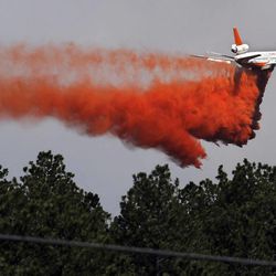 A fire-fighting slurry plane makes a pass in preparation drops its load on a wildfire in the Black Forest area north of Colorado Springs, Colo., on Wednesday, June 12, 2013. The number of houses destroyed by the Black Forest fire could grow to around 100, and authorities fear it's possible that some people who stayed behind might have died. (AP Photo/Brennan Linsley)