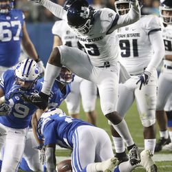 Utah State Aggies safety Jontrell Rocquemore (3) leaps over Brigham Young Cougars running back Squally Canada (22) after tackling him for a loss during the Utah State versus BYU football game at LaVell Edwards Stadium in Provo on Friday, Oct. 5, 2018.