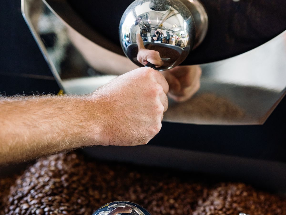 A person works on a machine that roasts beans at Tenfold Coffee Company in the Heights.