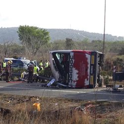 Emergency services personnel stand at the scene of a bus accident crashed on the AP7 highway that links Spain with France along the Mediterranean coast near Freginals halfway between Valencia and Barcelona early Sunday, March 20, 2016. The bus was reportedly hired out to carry students to and from a fireworks festival in Valencia and was on the return leg of its journey when the accident happened.
