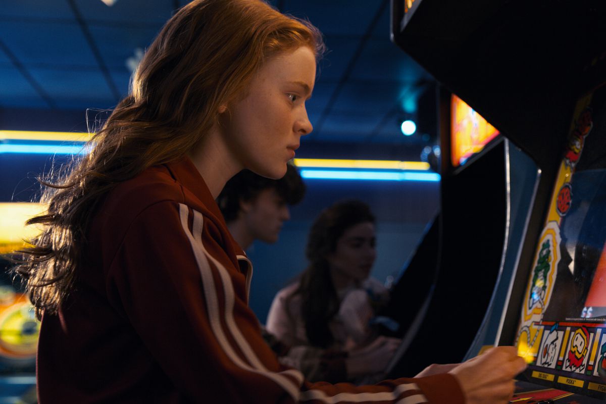 Stranger Things 2 - Max Mayfield, a young woman with red hair, plays an arcade game.