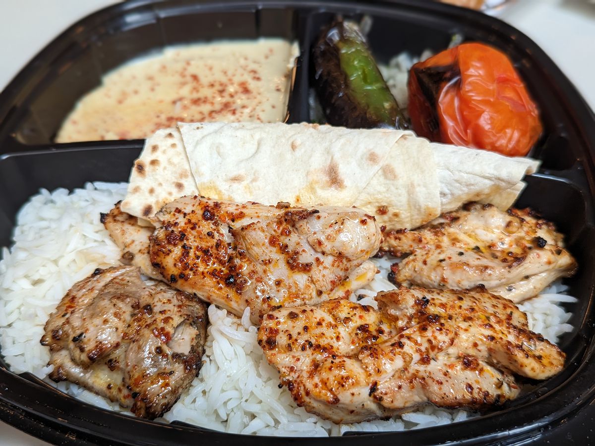 Chicken kebabs from Mini Kabob in Topanga Social over white rice in a black plastic tray.