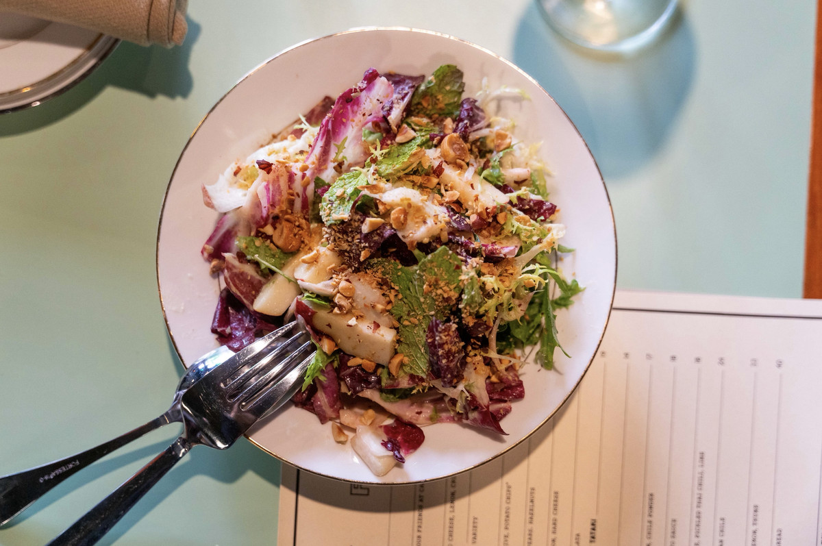 A plate of dressed greens comes topped with creamy celery root dressing at hazelnuts at Street Disco.