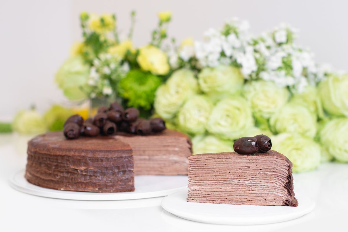 Chocolate layered mille crepe cakes with chocolate frosting, set in front of flowers.