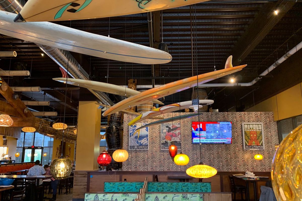 A dining room with surfboards hanging from the ceiling. 